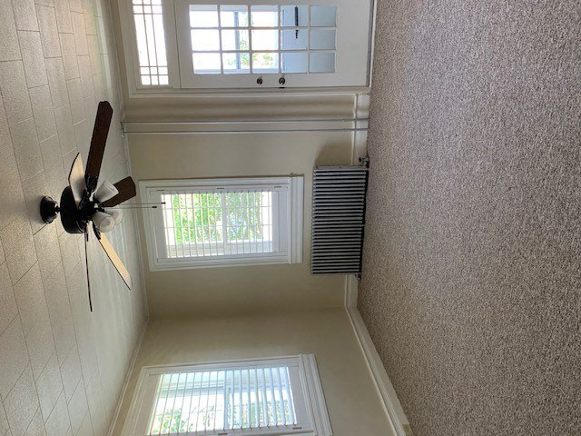 A ceiling fan is mounted on a wall in a room with a window.